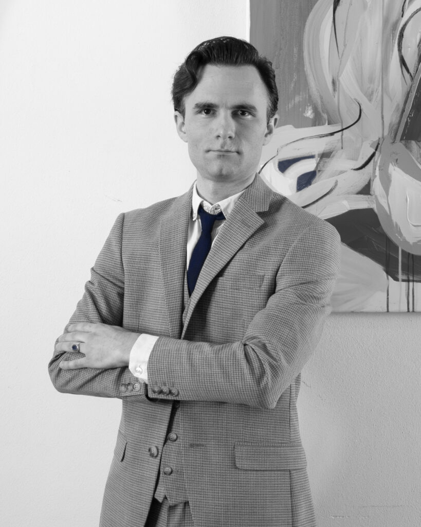 Dominik Imhof at Imhof Fine Arts gallery in Maastricht in front of a painting by Dick Berckenkamp.